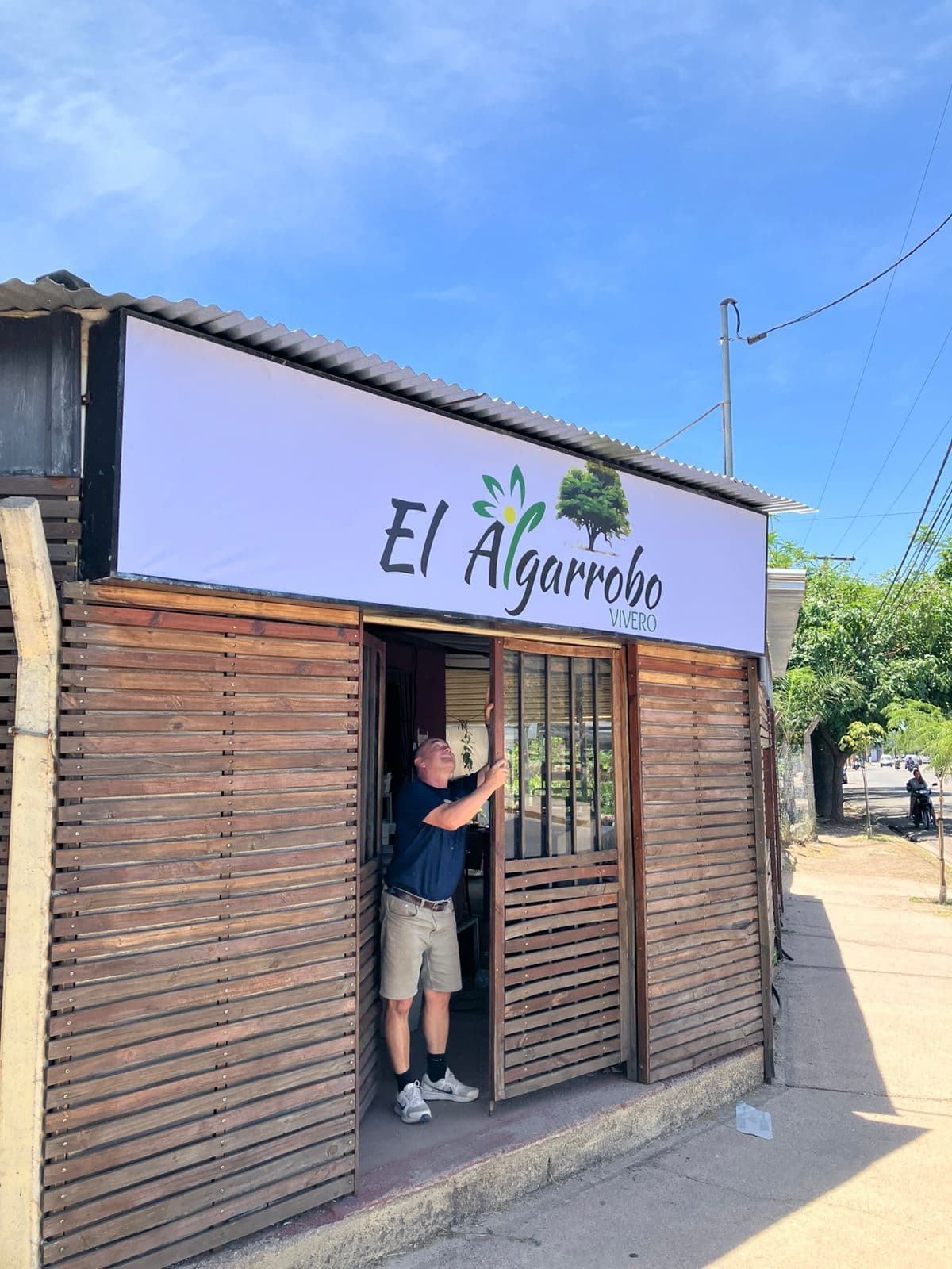 Cartel del vivero El Algarrobo sobre pared amarilla